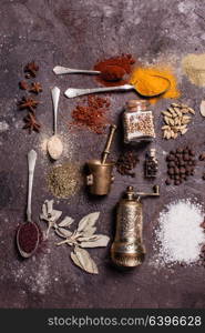 Flat lay composition of various spices and mortars over brown slate background, top view. Flat lay spices