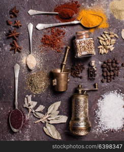 Flat lay composition of various spices and mortars over brown slate background, top view. Flat lay spices