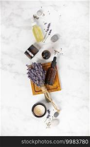 Flat lay composition with lavender flowers, candle and essential oil on white marble background