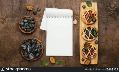 flat lay delicious fruit pies with plums notebook