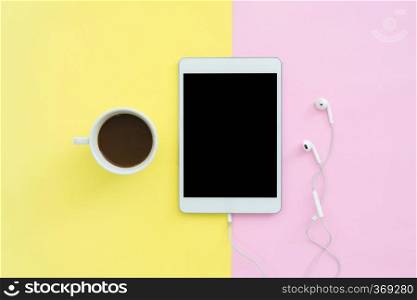 Flat lay design of travel in summer concept - Top view of an blank mock up tablet and coffee cup on pink yellow pastel color screen with copy space. Travel on summer trip on pastel color background.