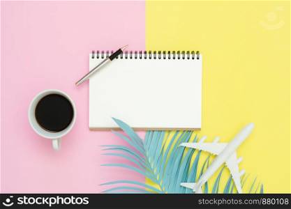 Flat lay design of travel summer concept - Top view mockup of blank paper notebook, pen, pastel leaf, coffee and plane on pink yellow pastel color screen. Travel in summer on pastel color background.