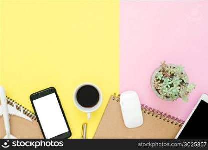 Flat lay design of travel summer concept - Top view of blank notebook, mock up smartphone, tablet, airplane, coffee cup and plane on pink yellow pastel color. Travel summer on pastel color background.