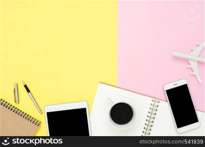 Flat lay design of travel summer concept - Top view of blank notebook, mock up smartphone, tablet, airplane, coffee cup and plane on pink yellow pastel color. Travel summer on pastel color background.