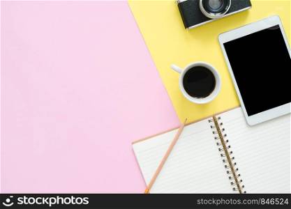 Flat lay design of travel summer - Top view mockup of white paper notebook, coffee, camera and tablet on pink and yellow pastel color screen with a copy space. travel on pastel color background.