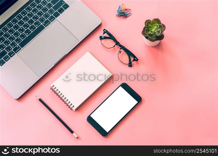 Flat lay design of workspace desk with laptop, blank notebook, smartphone, pencil, stationery with copy space background