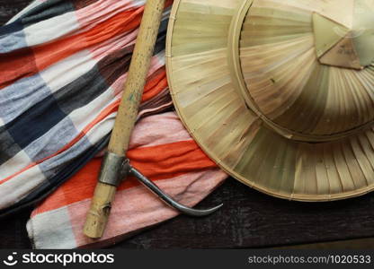 flat lay details showing the tools and colorful clothing and bamboo woven hat of a traditional Northern Thailand Thai Elephant Mahoot trainer, Southeast Asia