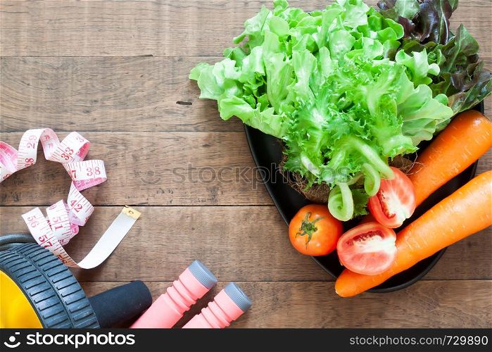 Flat lay, Health and fitness concept. Vegetables and fitness equipments on wooden background