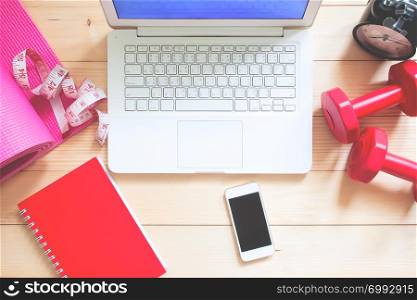 Flat lay health and insurance concept. Laptop computer and mobile device on workspace desk with fitness equipments