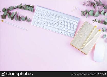 Flat lay home office workspace. Flat lay home office workspace - white modern keyboard with female accessories and green eucaliptus on pink background