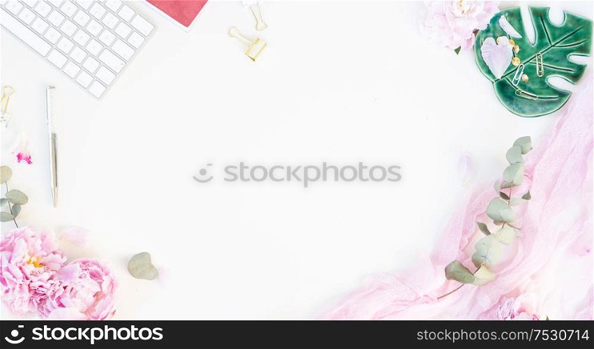Flat lay home office workspace frame - modern keyboard with female accessories and peony flowers, copy space on white background banner. Top view home office workspace