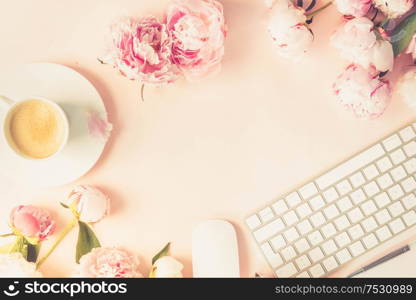 Flat lay home office workspace frame - modern keyboard with female accessories and fresh peony flowers, copy space on pink background, toned. Top view home office workspace