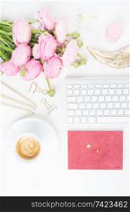 Flat lay home office workspace - modern keyboard with cup of coffee and pink ranunculus flowers. Top view home office workspace