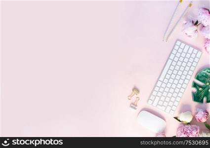 Flat lay home office workspace - modern keyboard with female accessories and peony flowers, copy space on plain pink background. Top view home office workspace