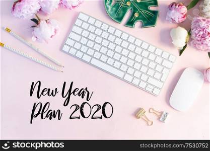 Flat lay home office workspace - modern keyboard with female accessories and peony flowers, copy space on pink background. Top view home office workspace