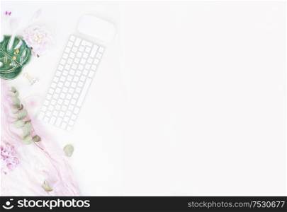 Flat lay home office workspace - modern silver keyboard with female accessories and peony flowers, copy space on white background. Top view home office workspace