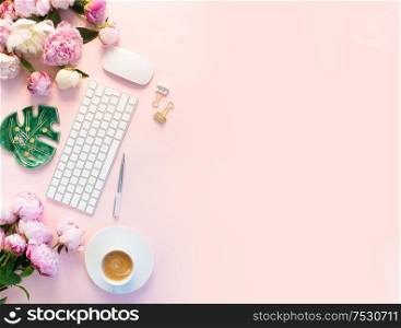 Flat lay home office workspace - modern white keyboard with cup of coffee and peony flowers, copy space on pink plain background. Top view home office workspace