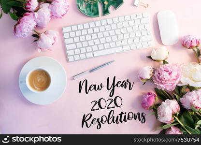 Flat lay home office workspace - modern white keyboard with cup of coffee and peony flowers, copy space on pink background. Top view home office workspace