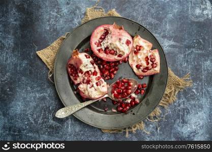 Flat lay image of torn Pomegranate fruit and seeds on textured rough background
