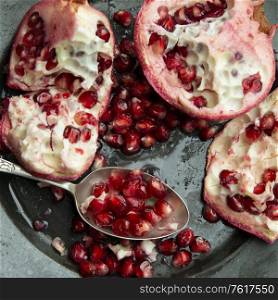 Flat lay image of torn Pomegranate fruit and seeds on textured rough background