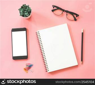 Flat lay mockup design of workspace desk with blank notebook, smartphone, stationery on pink pastel color with copy space