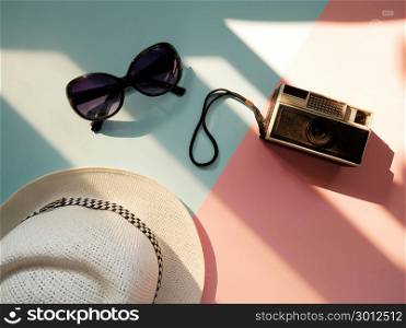 Flat lay of accessories items for travelr with camera, hat and sunglasses on colorful background. Holiday concept.