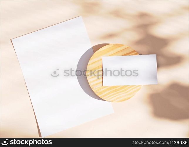 Flat lay of branding identity business name card and blank paper on yellow background, light and shadow shape leaves, minimal concept for design