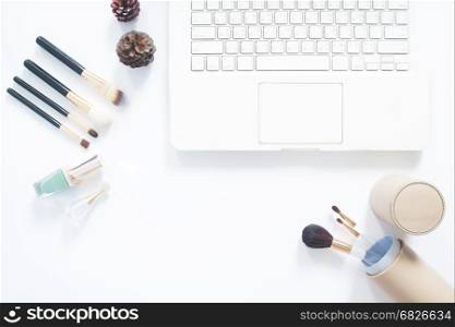 Flat lay of brushes with laptop computer on white background with copy space