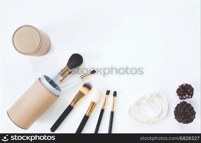 Flat lay of brushes with pearl bracelet on white background with copy space
