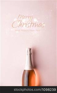 Flat lay of Celebration. Champagne bottle on pink background, top view. Christmas background with festive decoration and text - Merry Christmas and Happy New Year.. Flat lay of Celebration. Champagne bottle on pink background with text