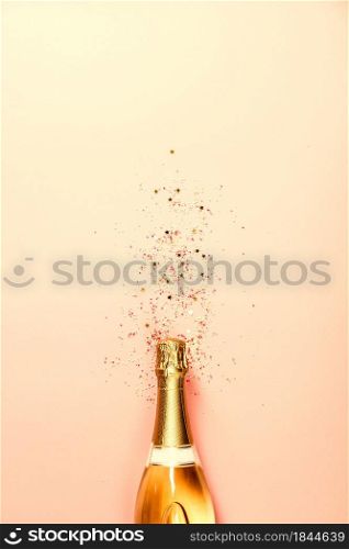 Flat lay of Celebration. Champagne bottle with ice cream sprinkles and golden star sprinkles on pink gradient background. Top view. Flat lay of Celebration. Champagne bottle with sprinkles on pink background.
