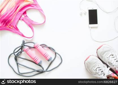 Flat lay of cellphone, pink sport bra, jump rope and sneaker on white background, Working out and healthy concept, top view