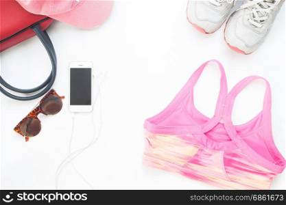 Flat lay of cellphone with pink sport bra and woman accessories on white background, Workout and Healthy concept, Top view