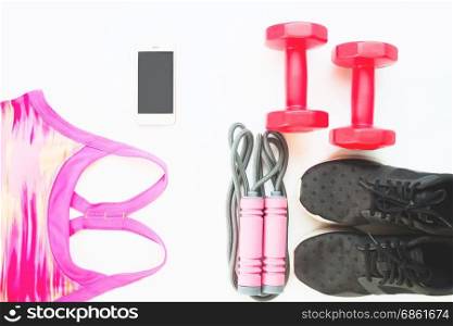 Flat lay of cellphone with pink sport bra, Jump rope and red dumbbells on white background, Workout and Healthy concept, Top view