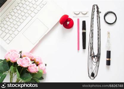 Flat lay of computer laptop with diamond ring, woman's accessories, cosmetic and pink rose, Top view on white background with copy space