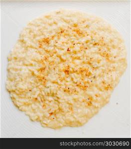 Flat-lay of delicious creamy risotto bowl with parmesan cheese on white plate. Flat-lay of delicious creamy risotto bowl with parmesan cheese on white plate.