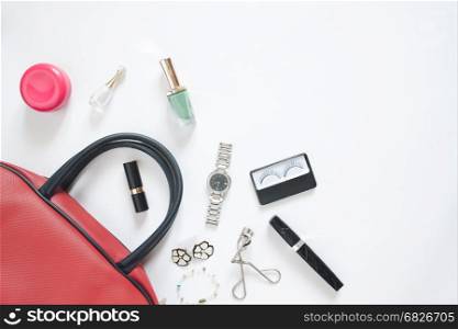 Flat lay of female items out of hand bag on white background
