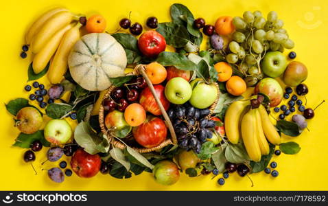 Flat-lay of fresh fruits and berries on yellow background. Top view. Vegetarian, clean eating, raw food concept