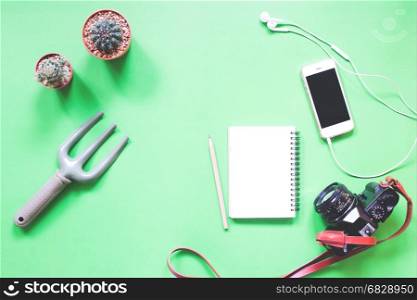 Flat lay of greeney with cactus, smartphone, notebook and camera