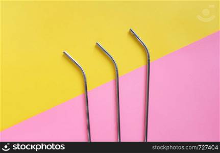 Flat lay of metallic stainless straws for drink on bright pink and yellow background, sustainable product lifestyle and zero waste concept, copy space