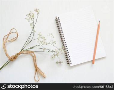 Flat lay of minimal workspace desk with notebook and flower, copy space