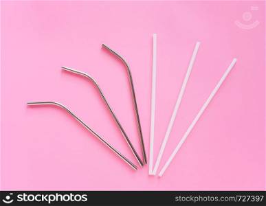Flat lay of reusable stainless steel straw with plastic straw on bright pink color background, sustainable lifestyle and zero waste concept