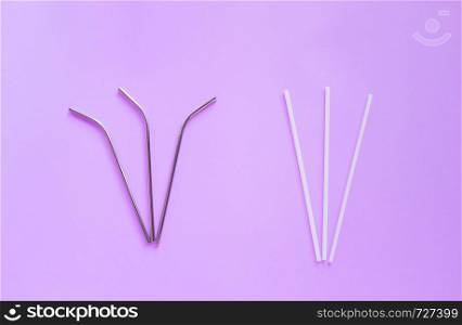 Flat lay of reusable stainless steel straw with plastic straw on bright purple color background, sustainable lifestyle and zero waste concept