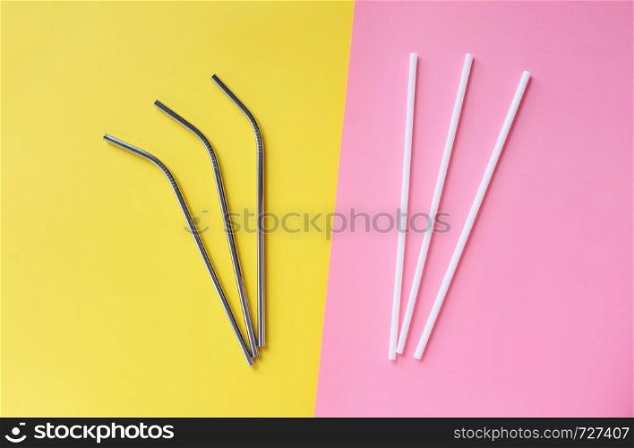 Flat lay of reusable stainless steel straw with plastic straw on bright pink and yellow color background, sustainable lifestyle and zero waste concept
