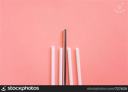 Flat lay of reusable stainless steel straw with plastic straw on bright orange color background, sustainable lifestyle and zero waste concept