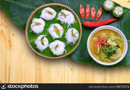 Flat lay of rice noodles with chicken green curry on wooden table decorations in vintage style