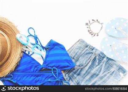 Flat lay of smartphone with bikini, goggles in blue color and summer items on white background, Summer vacation