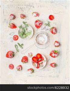 Flat lay of strawberries , powdered sugar and mint leaves on white shabby chic wooden background, top view