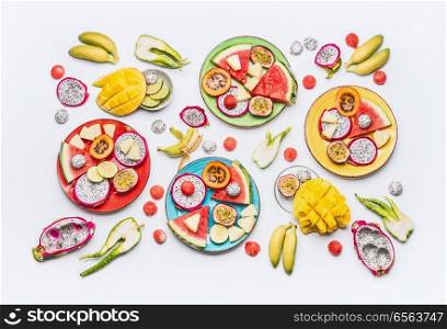 Flat lay of summer various colorful sliced tropical fruits and berries plates and bowls on white  background with ingredients, top view.  Clean and healthy lifestyle  background