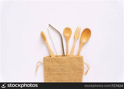 Flat lay of sustainable products, wooden spoon, stainless straw in natural sack bag on white background, eco friendly and zero waste concept